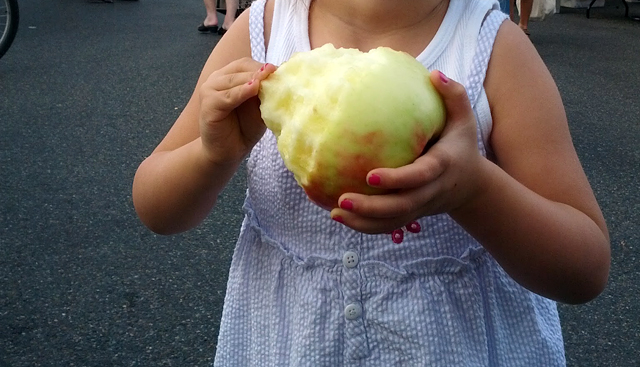 girl holding honeycrisp apple at farmers market