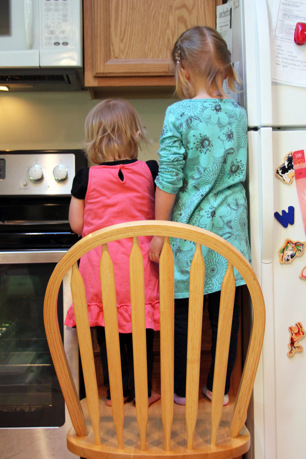 girls standing on chair making food