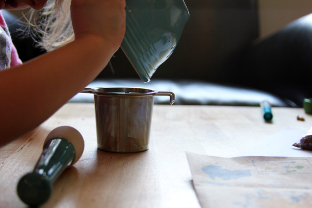 kid pouring mortar tea into strainer